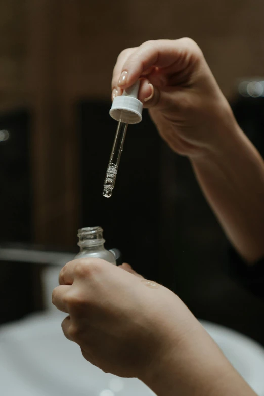 a close up of a person putting something in a bottle, image apothecary, essence, thumbnail, small in size