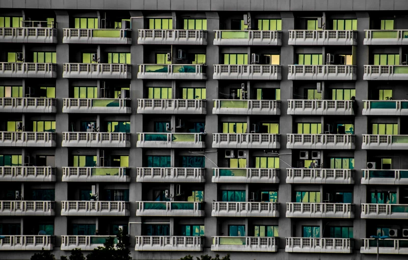 a tall building with lots of windows and balconies, a photo, inspired by Andreas Gursky, pexels, brutalism, neon green, thailand, keys, crenellated balconies