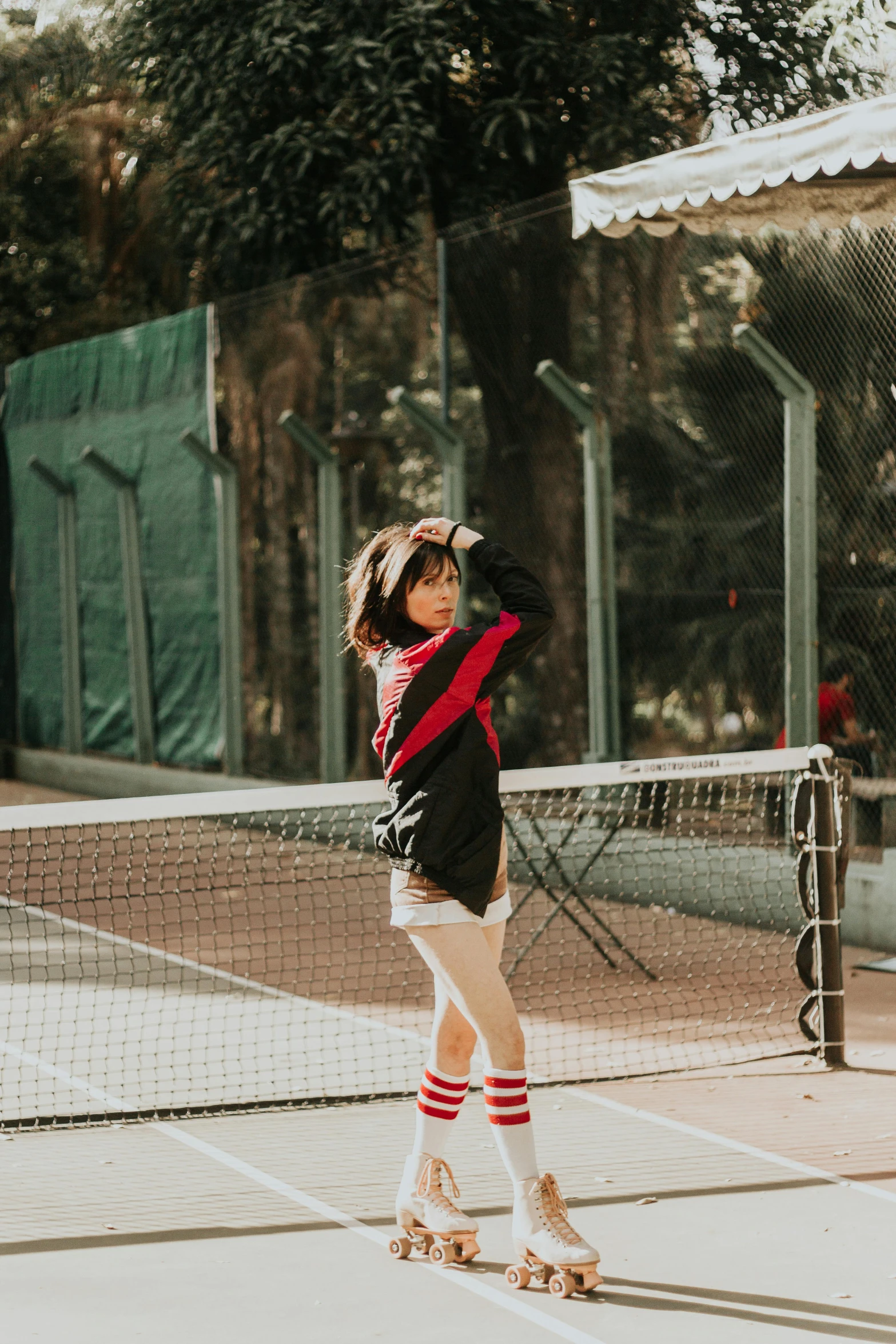 a little girl standing on a tennis court holding a racquet, by Julia Pishtar, pexels contest winner, black and red jacket, white stripes all over its body, black haired girl wearing hoodie, with his back turned