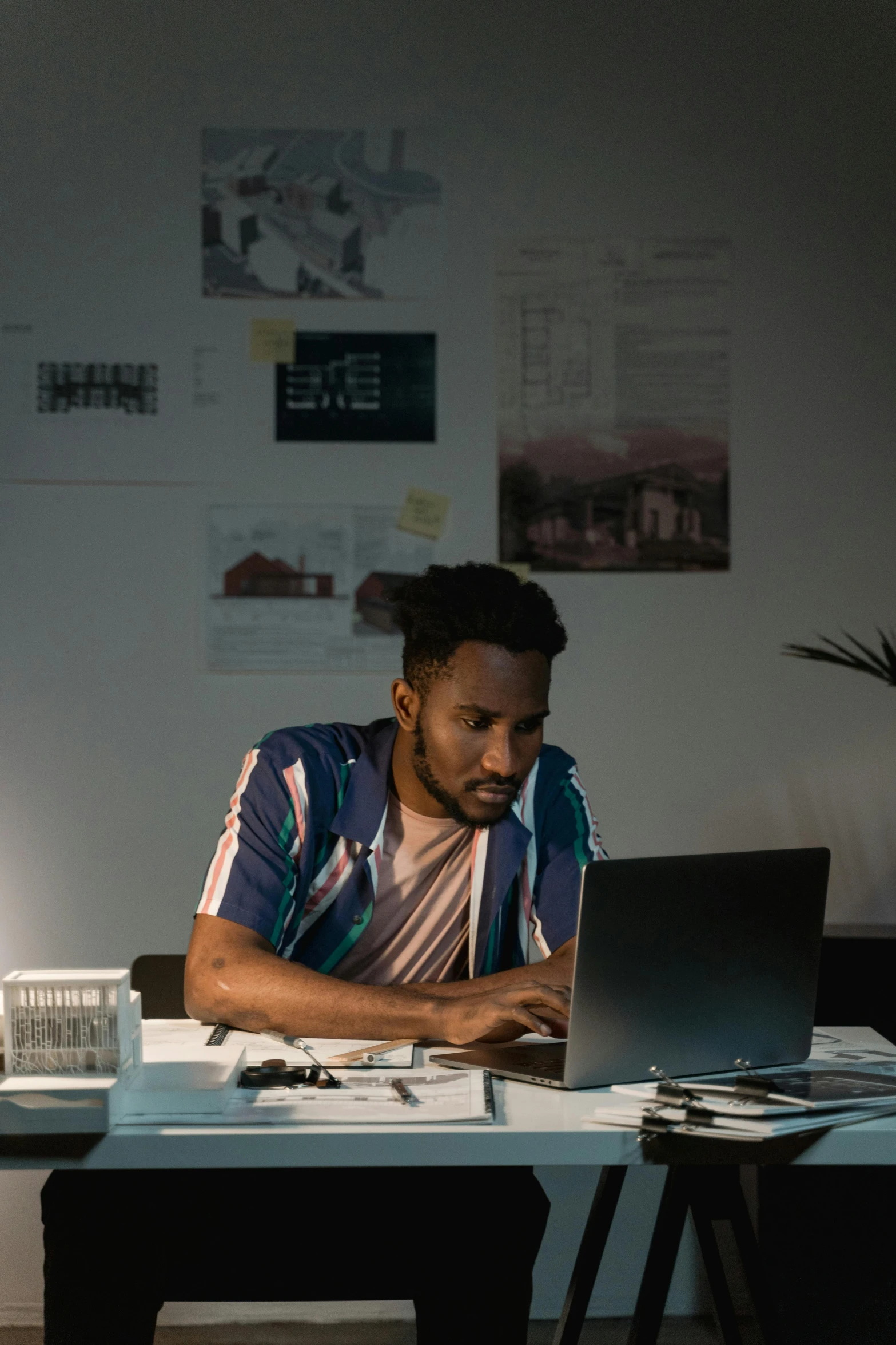 a man sitting at a desk using a laptop computer, inspired by Afewerk Tekle, pexels contest winner, bisexual lighting, ignant, someone lost job, looking serious