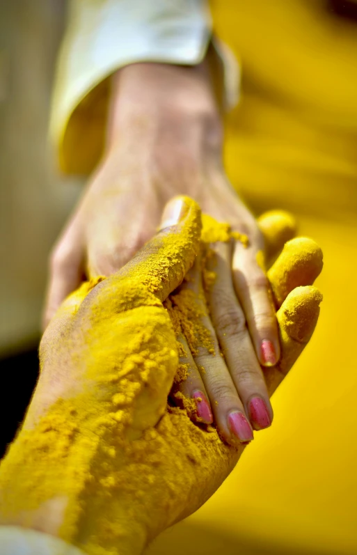 a close up of a person holding a person's hand, inspired by Steve McCurry, bright yellow color scheme, vibrant powder paints, hindu, purity