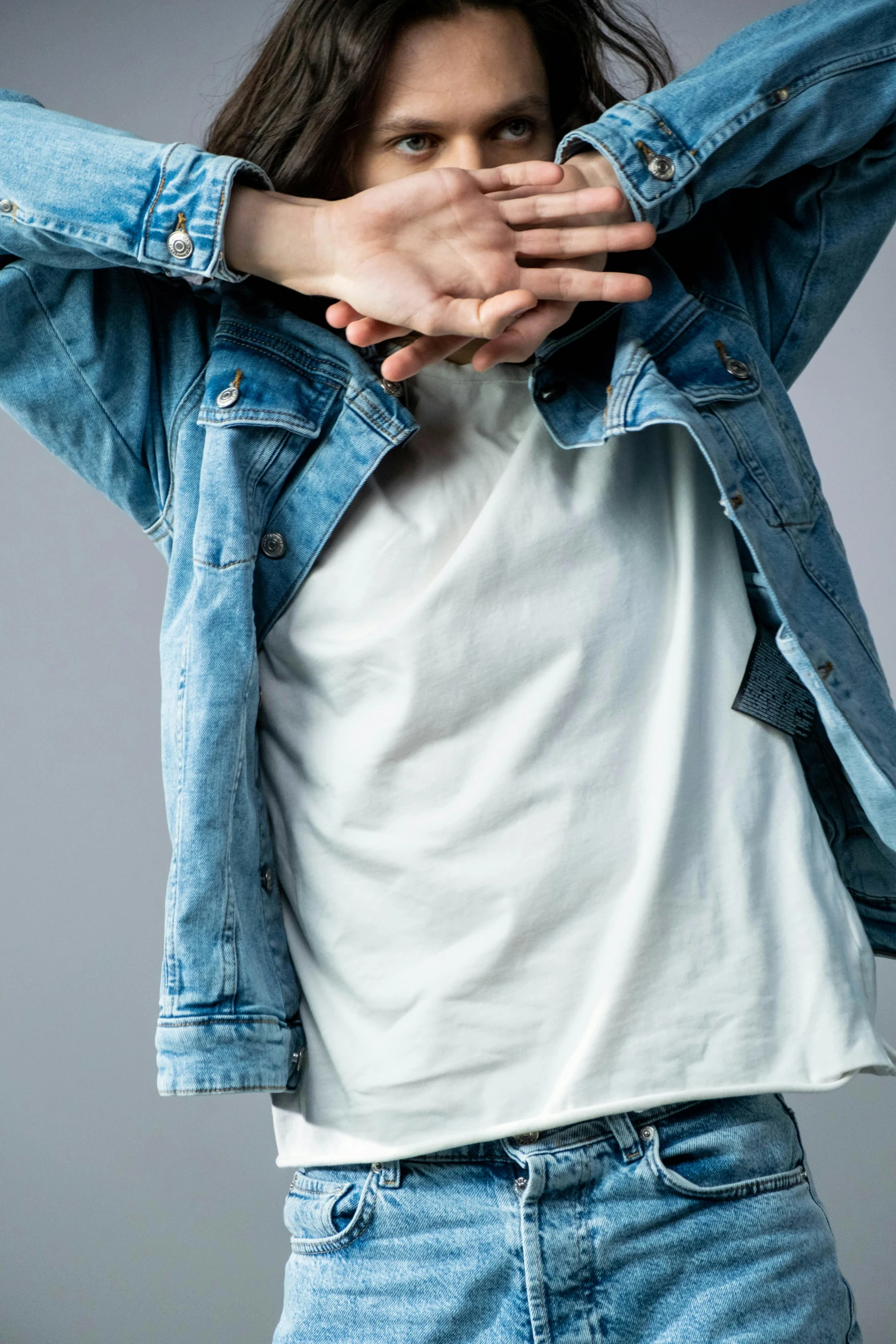 a man with long hair wearing a denim jacket, an album cover, trending on pexels, hyperrealism, dressed in a white t-shirt, androgynous person, touching her clothes, detailed product image