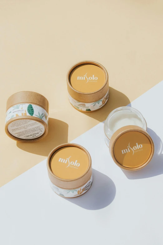 three jars of lip butter sitting on top of a table, yotobi, textured base ; product photos, mulato, skyline showing
