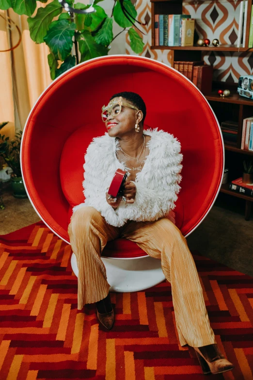 a man sitting in a red chair in a living room, by Winona Nelson, trending on pexels, maximalism, girl wearing round glasses, portrait willow smith, a woman holding an orb, bowl haircut