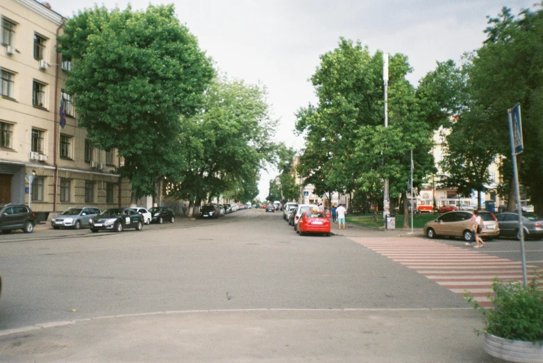 a red bus driving down a street next to tall buildings, unsplash, hyperrealism, lviv, 1999 photograph, a park, summer street near a beach