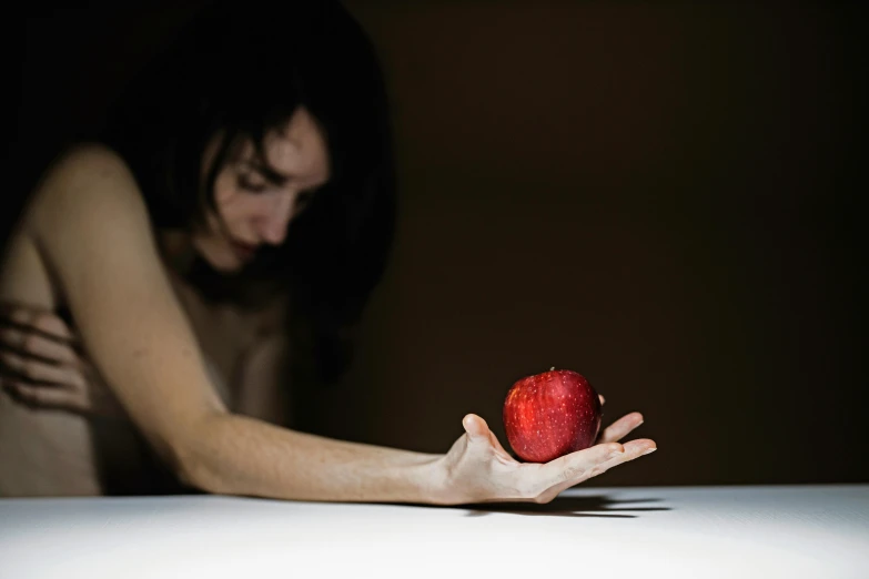 a woman holding a red apple in her hand, inspired by Orazio Gentileschi, crawling out of a dark room, profile image, on a table, profile pic