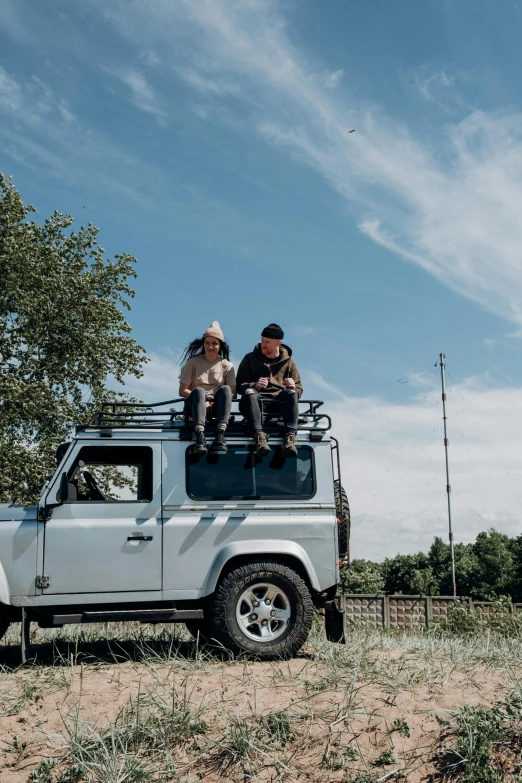 a group of people sitting on top of a truck, land rover defender, swedish countryside, 2019 trending photo, 2 5 6 x 2 5 6 pixels