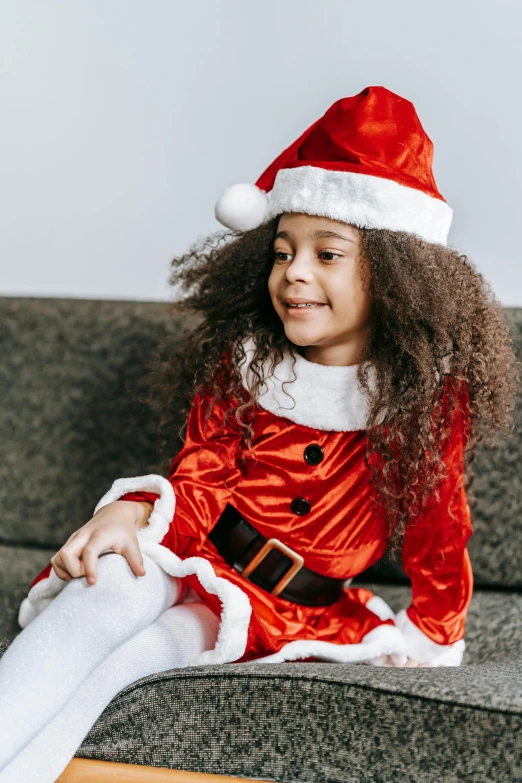 a little girl dressed as santa claus sitting on a couch, pexels, long afro hair, girl wearing uniform, next gen, gif