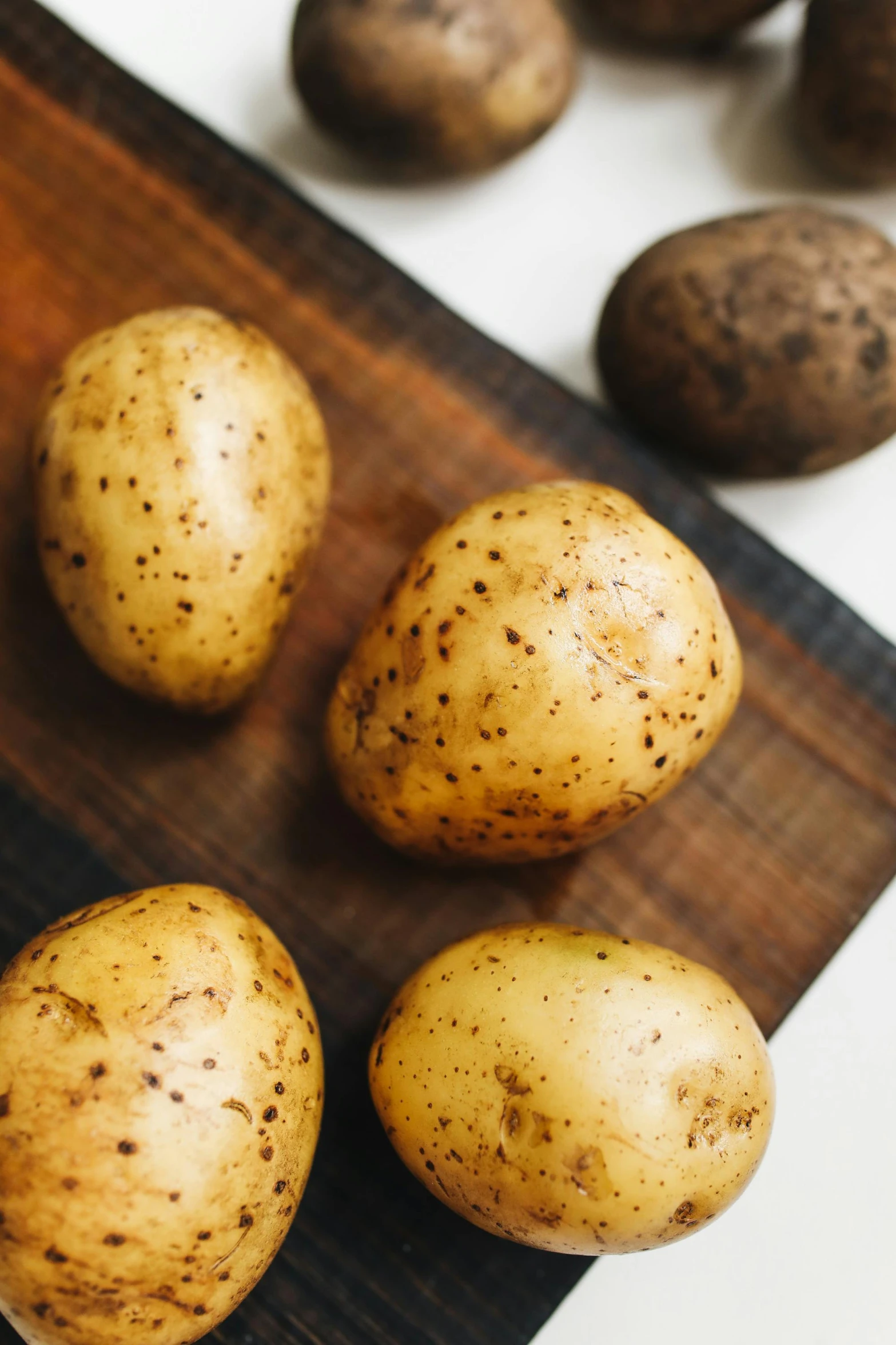 potatoes sitting on top of a wooden cutting board, a portrait, unsplash, gold speckles, white, f / 2 0, brown