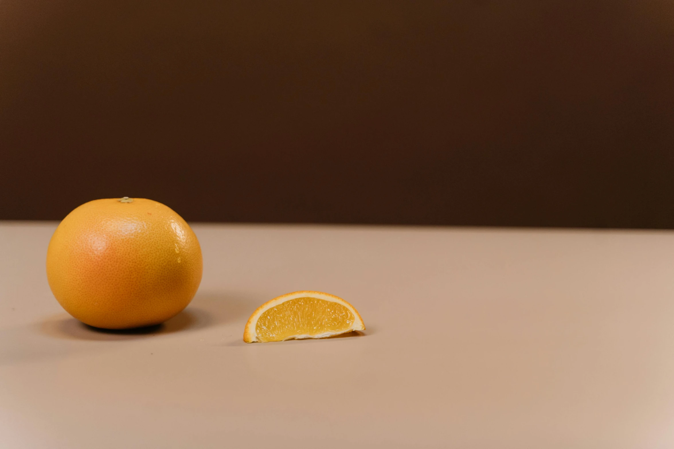 an orange cut in half sitting on a table, a still life, trending on pexels, background image, brown, hyperminimalist, orange mist