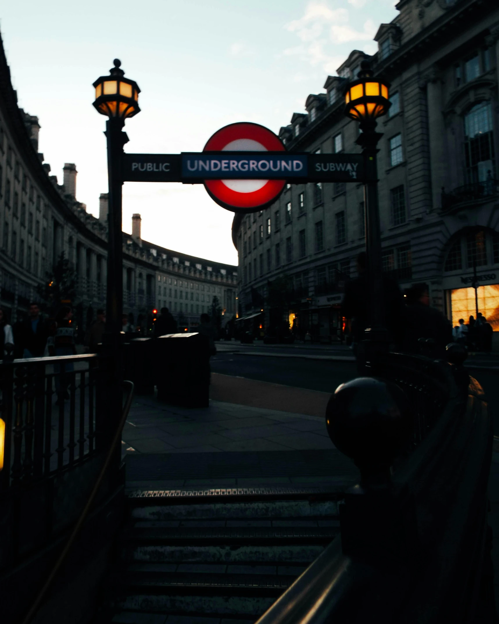 a red and white sign sitting on the side of a road, an album cover, pexels contest winner, art nouveau, london underground tube station, at dusk!, lgbtq, view from the bottom