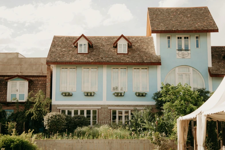 a white tent sitting in front of a blue house, by Carey Morris, unsplash, arts and crafts movement, french village exterior, cyan shutters on windows, normandy, vines. tiffany blue