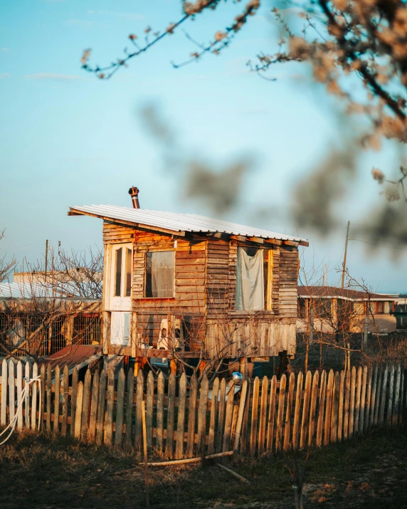 a small house sitting in the middle of a field, by Emma Andijewska, unsplash, renaissance, shanty town, wooden toilets, west slav features, trailer park