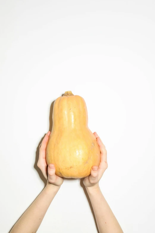 a person holding a squash in front of their face, inspired by Sarah Lucas, unsplash, showstudio, plain background, ignant, 🐿🍸🍋