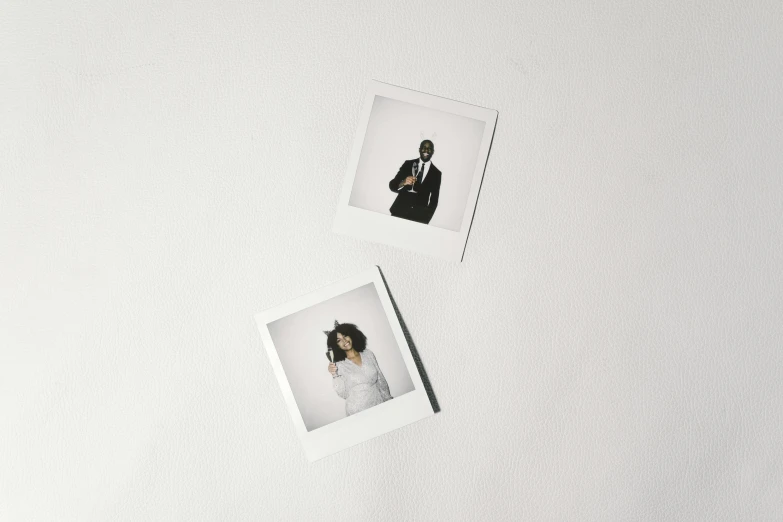 a couple of polaroids sitting on top of a white table, r&b, two characters, plain background, product image