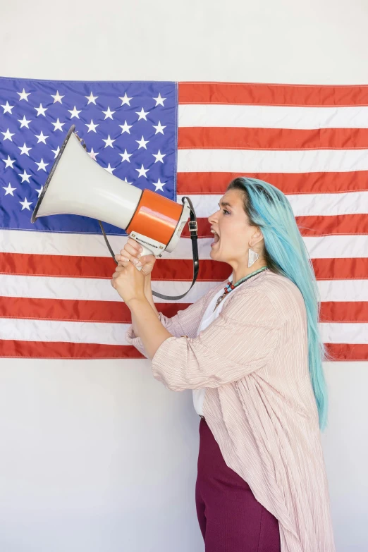 a woman holding a megaphone in front of an american flag, a colorized photo, trending on pexels, turquoise hair, subreddit / r / whale, 🚿🗝📝, language