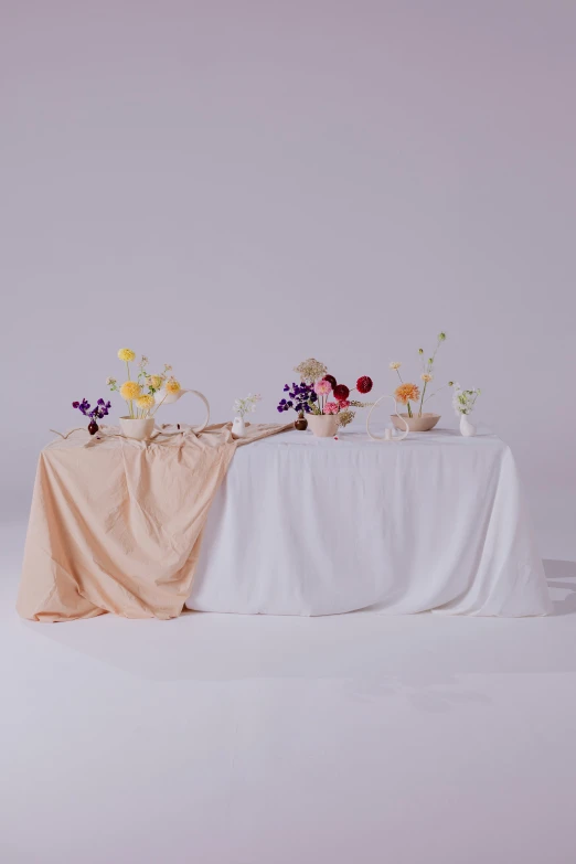 a table that has a bunch of flowers on it, inspired by Pierre-Joseph Redouté, unsplash, large draped cloth, on white background, off - white collection, pastel color theme