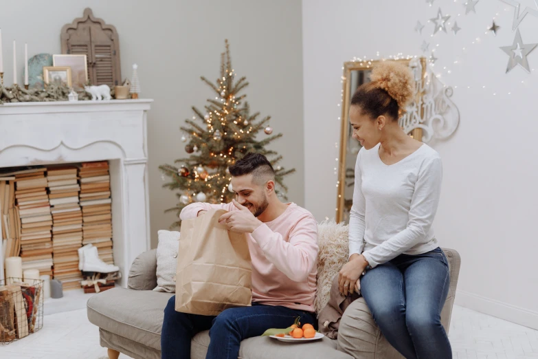 a man and woman sitting on a couch in front of a christmas tree, getting groceries, profile image, serving suggestion, extra crisp image