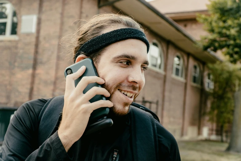 a man with a headband talking on a cell phone, a photo, inspired by James Ardern Grant, trending on pexels, shroud, telephone, college, australian