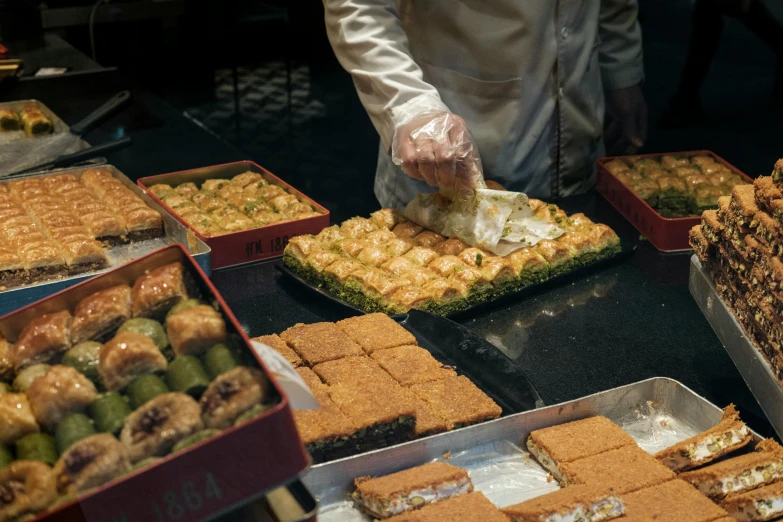 a number of trays of food on a table, hurufiyya, cake in hand, surrounding the city, squares, gooey