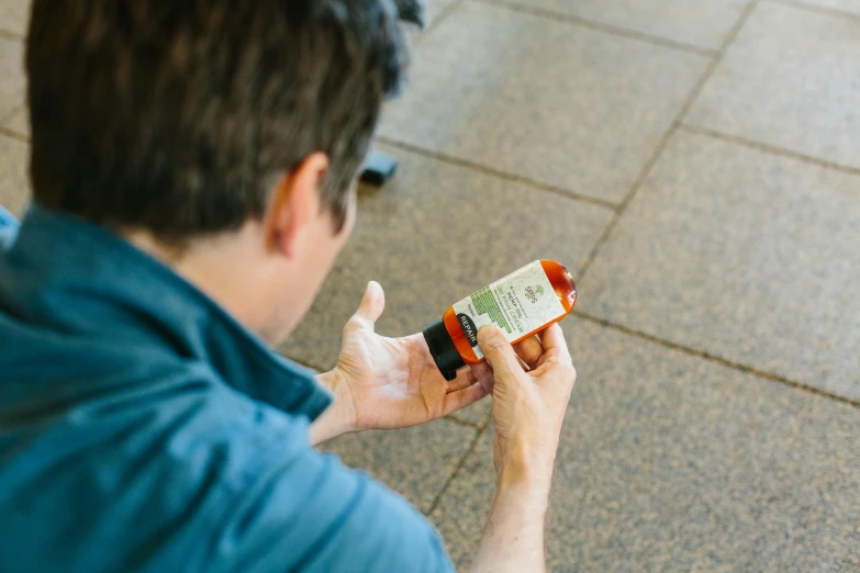 a man sitting on the ground using a cell phone, by Matthew Smith, unsplash, holding hot sauce, medical labels, profile image, back