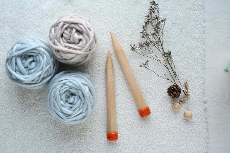 a close up of yarn and knitting needles on a table, inspired by Toss Woollaston, blue and orange, pointè pose, nimbus, 2 colours