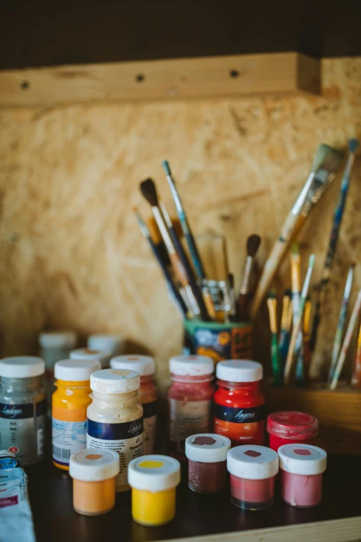 a bunch of paint sitting on top of a wooden table, in a workshop, world renowned artists, brushes, our art corner