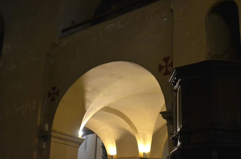 a clock mounted to the side of a building, an album cover, by Cagnaccio di San Pietro, pexels contest winner, romanesque, in dark corridor, white sweeping arches, lit from below with red lighting, parce sepulto