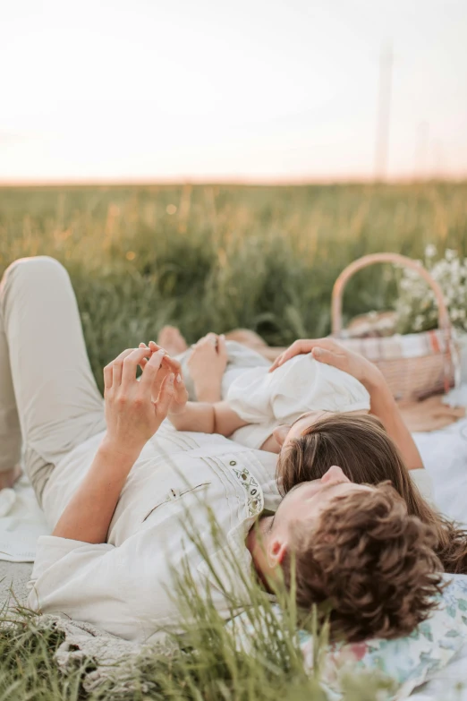 a man and woman laying on a blanket in a field, pexels contest winner, romanticism, father with child, having a picnic, white, soft glow