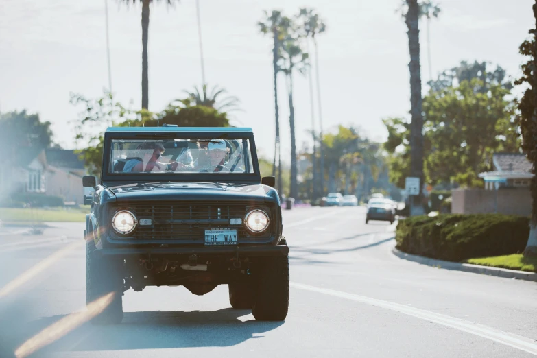 a jeep driving down a street with palm trees in the background, a portrait, unsplash, renaissance, restomod, near the beach, sunday afternoon, everyone having fun