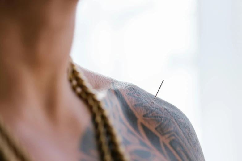 a close up of a person with a tattoo on, trending on pexels, acupuncture treatment, shoulder level shot, thin spikes, shot on 35 mm