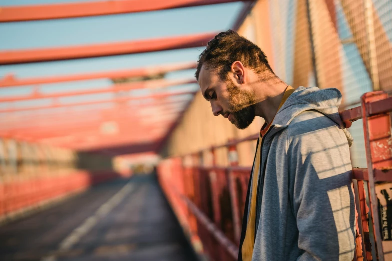 a man standing on a bridge looking down, pexels contest winner, happening, ponytail and beard, wearing a track suit, avatar image, golden hour photo