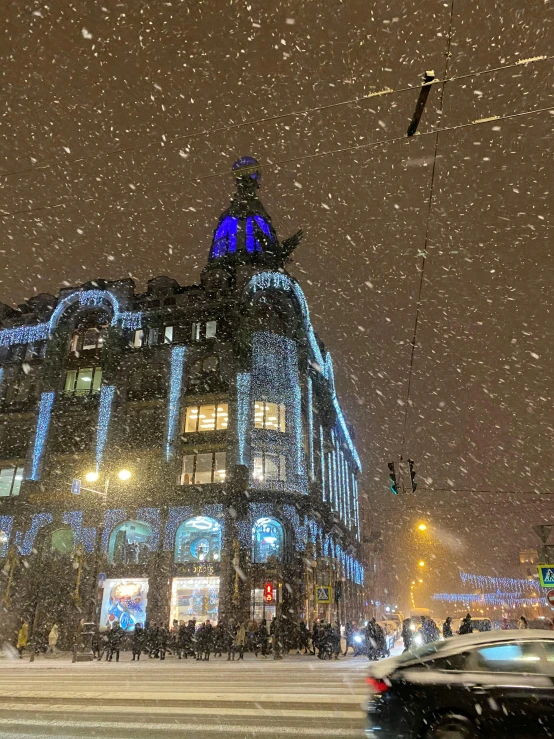 a car driving down a snowy street next to a tall building, by Emma Andijewska, pexels contest winner, art nouveau, high blue lights, city snowing with a lot of snow, thumbnail, in moscow centre