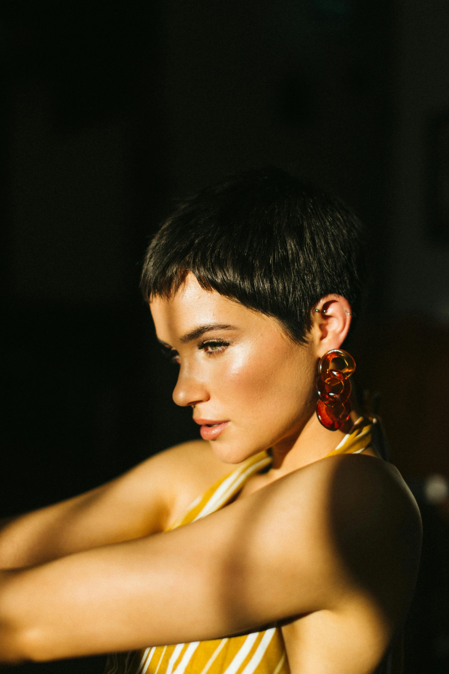 a woman in a yellow and white striped dress, an album cover, by Winona Nelson, trending on pexels, pixie cut, earring, backlighted, looking away