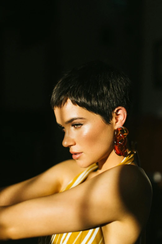 a woman in a yellow and white striped dress, an album cover, by Winona Nelson, trending on pexels, pixie cut, earring, backlighted, looking away