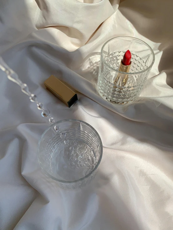 a couple of glasses sitting on top of a bed, inspired by Hedi Xandt, featured on instagram, crystal cubism, vibrent red lipstick, super detail of each object, cocktail in an engraved glass, 2019 trending photo