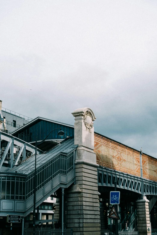 a train station with a cloudy sky in the background, unsplash, art nouveau, external staircases, 1990s photograph, fenway park, bridges and railings