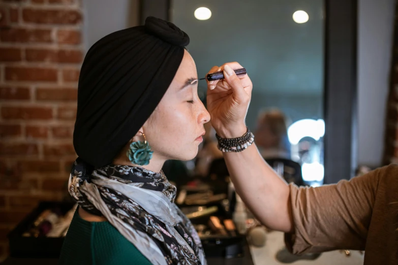 a woman putting makeup on another woman's face, pexels contest winner, hyperrealism, wearing a head scarf, jackie tsai style, in a medium full shot, relaxed eyebrows