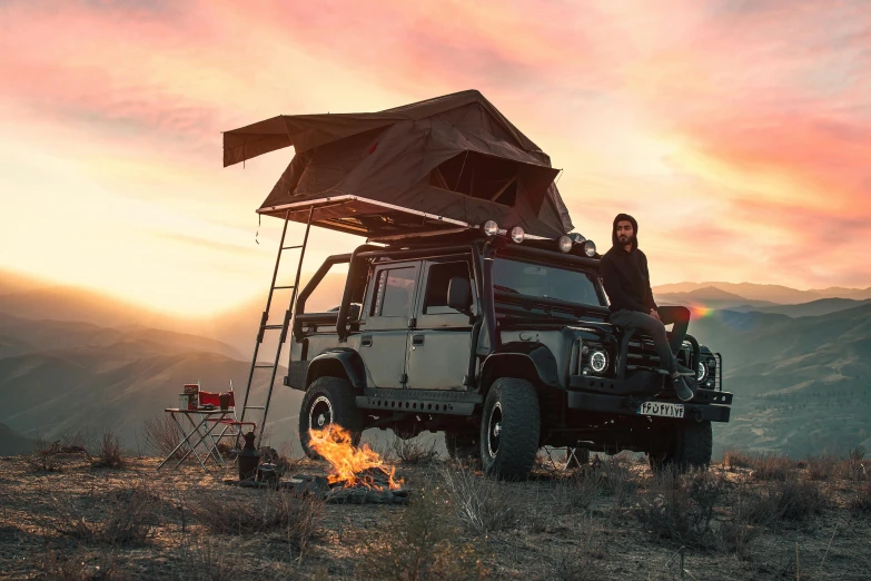 a couple of people sitting on top of a truck, land rover defender, barrel fires and tents, avatar image, ultrawide cinematic