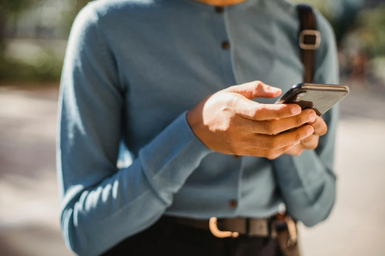 a close up of a person holding a cell phone, by Niko Henrichon, trending on pexels, happening, wearing a light blue shirt, waist - up, afternoon, avatar image
