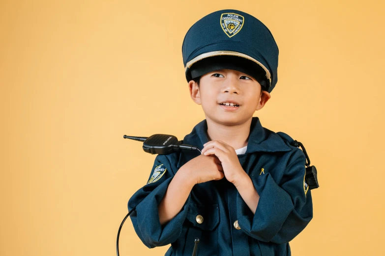 a young boy in a police uniform holding a microphone, by Alison Geissler, pexels, avatar image, costume, darren quach, police station