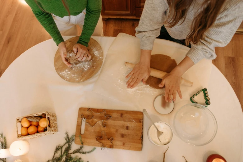 a couple of people that are standing around a table, inspired by Béni Ferenczy, trending on pexels, baking cookies, seasonal, bottom angle, cooking