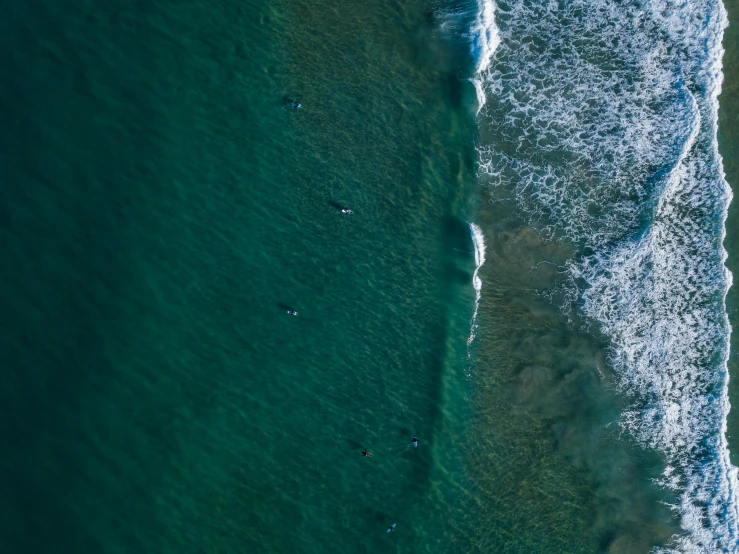 a large body of water next to a beach, by Niko Henrichon, unsplash contest winner, surf, deep green, in a row, a high angle shot