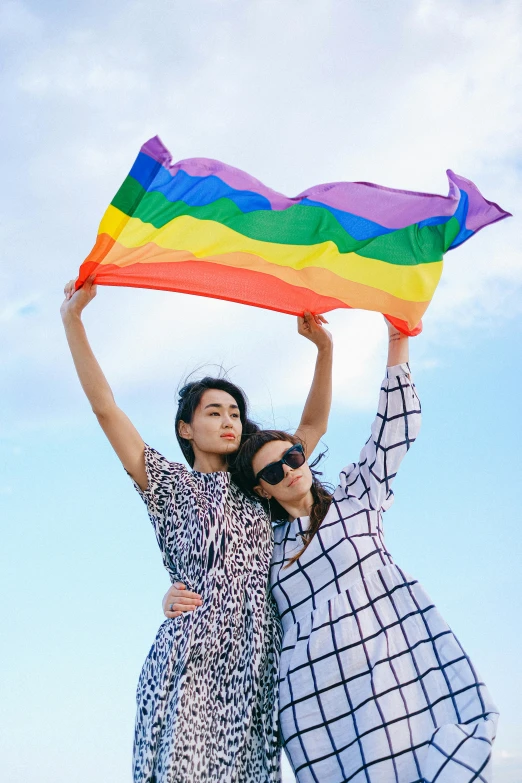 two women standing next to each other holding a rainbow flag, a photo, by Okuda Gensō, trending on unsplash, color field, 🚿🗝📝