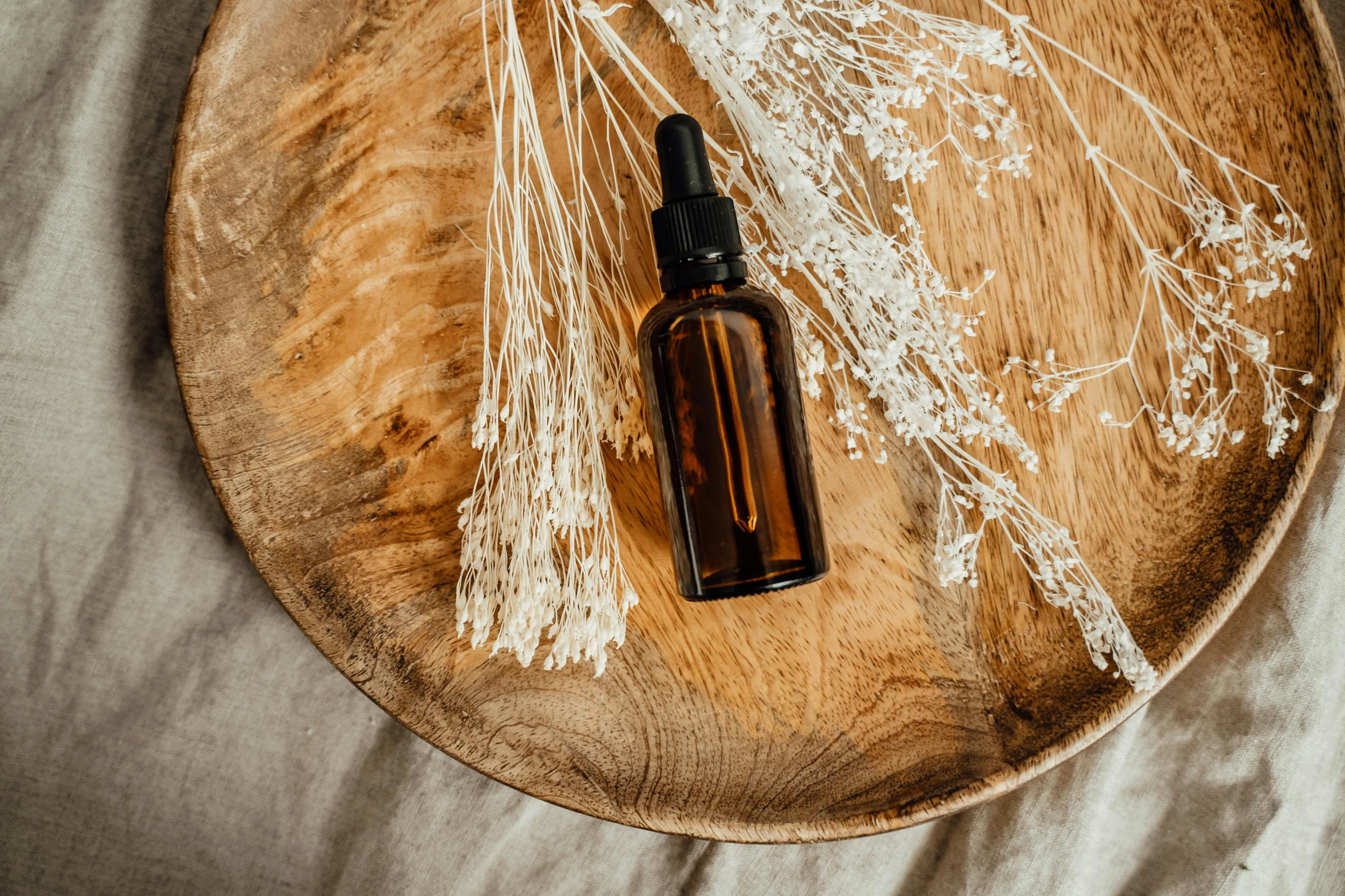 a bottle of essential oil on a wooden plate, by Andries Stock, trending on pexels, photoshoot for skincare brand, thumbnail, brown, handcrafted