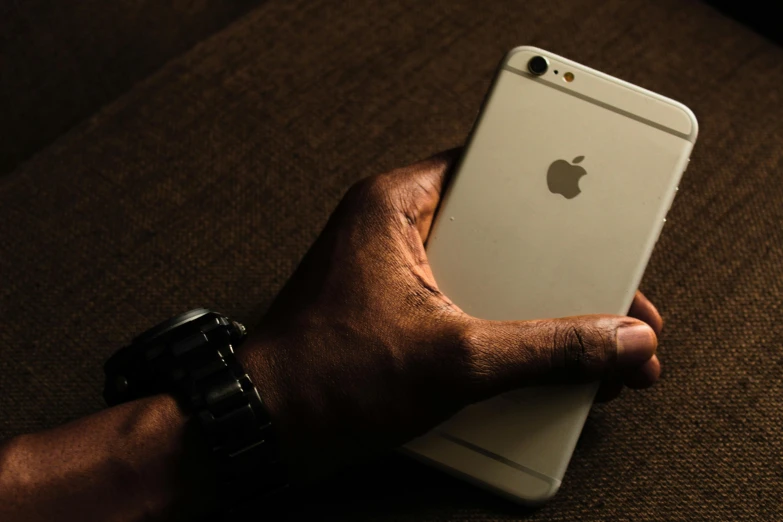 a close up of a person holding a cell phone, unsplash, hyperrealism, brown skin, shot on iphone 6, grain”, with apple