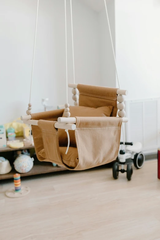 a baby sitting on a swing in a room, with two front pockets, brown:-2, diy, ji-min