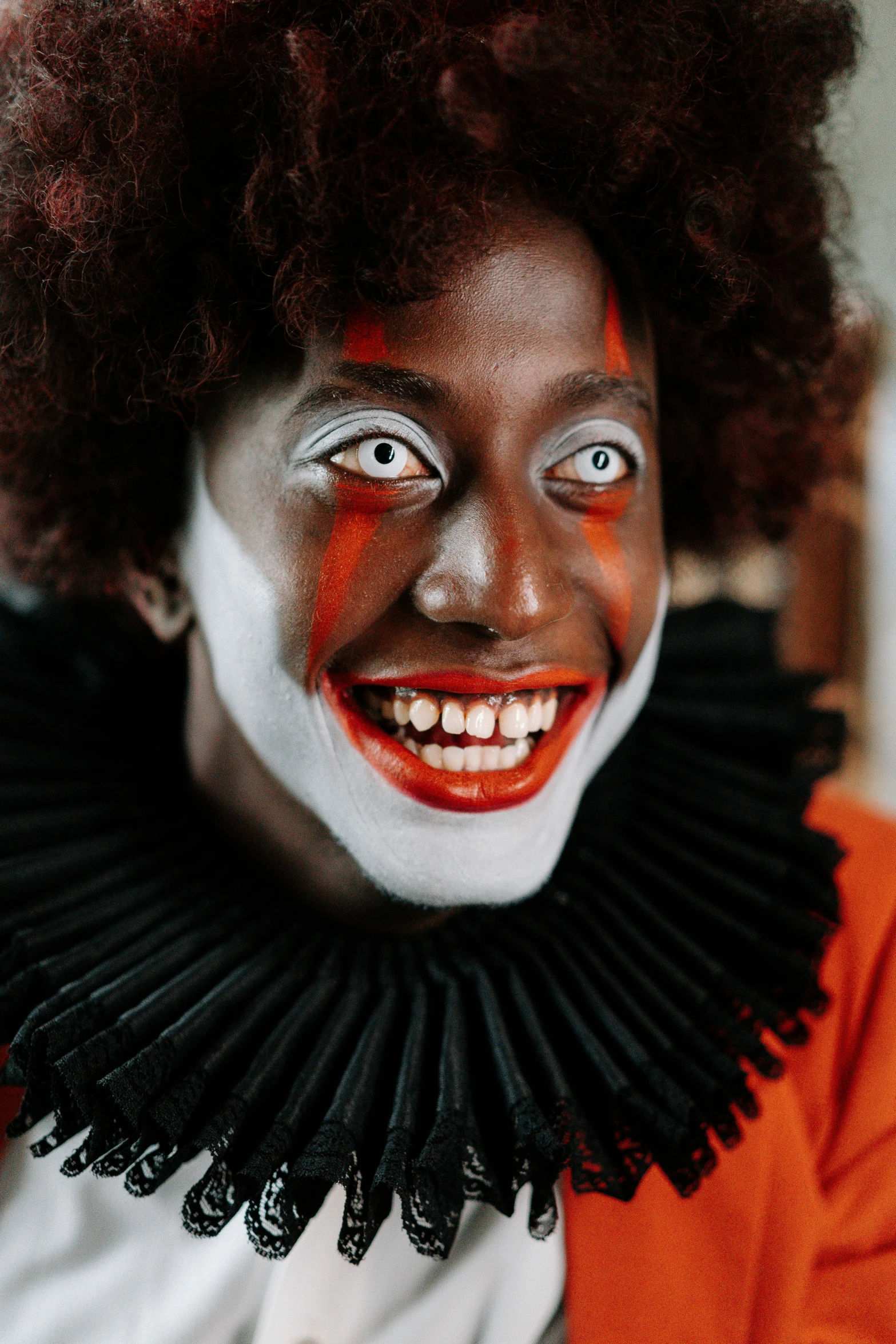 a close up of a person wearing clown makeup, an album cover, pexels contest winner, renaissance, brown skin man with a giant grin, bright orange eyes, black sclera white pupil, clown girl