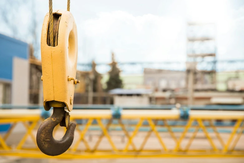 a close up of a crane hook with a building in the background, a portrait, unsplash, yellow, large scale photo, thumbnail, focus on full - body