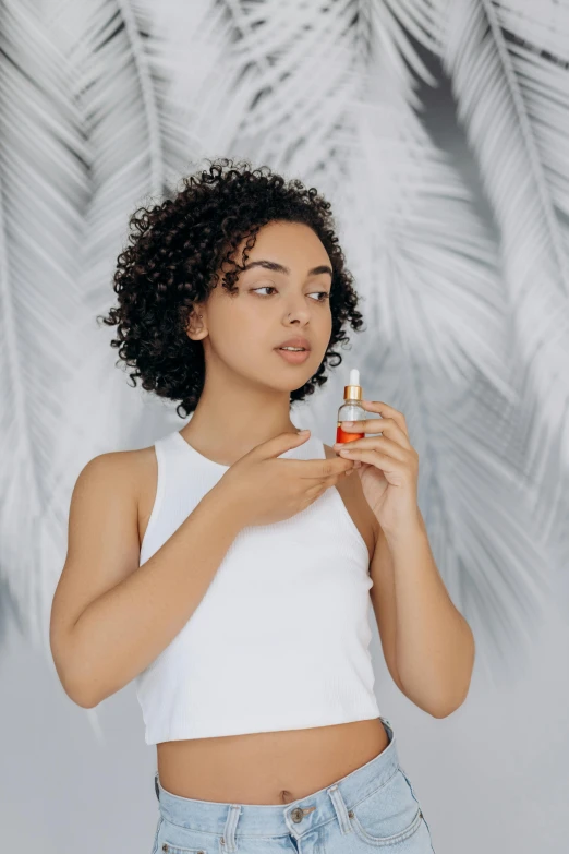 a woman standing in front of a palm tree, carrying a bottle of perfume, with textured hair and skin, on a gray background, curls on top